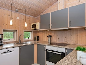 Eine moderne Küche mit Holzschränken, einem Einbauofen und einer Mikrowelle.