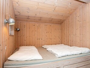 A small, wooden cabin room with two beds, a wall-mounted light fixture, and a wooden ceiling. - 4 Star Holiday Home in Juelsminde (Horsens)