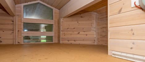 A room with a sloped ceiling, wooden walls, and a large window.