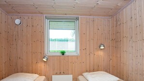 Een kamer met twee bedden, een raam met uitzicht, een radiator en twee wandlampen.