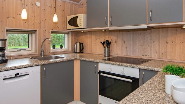 Een moderne keuken met houten lambrisering, een ingebouwde magnetron, een Bosch oven en hanglampen.