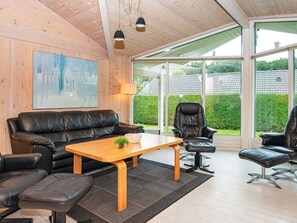 A modern living room with a leather sofa, a wooden coffee table, and a black office chair.