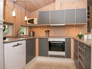 A modern kitchen with wooden paneling, a Bosch oven, and granite countertops. - 4 Star Holiday Home in Juelsminde (Horsens)