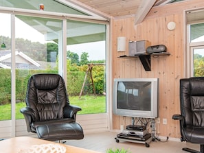 Ein modernes Wohnzimmer mit Ledersesseln, einem Fernseher und einer Holzwand.