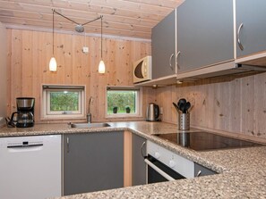 A modern kitchen with wooden walls, granite countertops, and stainless steel appliances. - 4 Star Holiday Home in Juelsminde (Horsens)