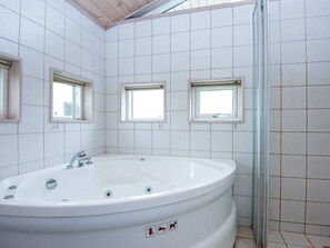 A bathroom with a large bathtub, three small windows, and tiled walls. - 4 Star Holiday Home in Juelsminde (Horsens)