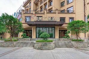 A hotel entrance with a modern facade, a staircase leading up to the entrance, and a well-maintained garden area. - Yuemei Wanxiang Hotel (Zunyi)