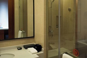A modern bathroom with a glass-enclosed shower, a large mirror, and a sink with a towel and a bag on the counter. - Yuemei Wanxiang Hotel (Zunyi)