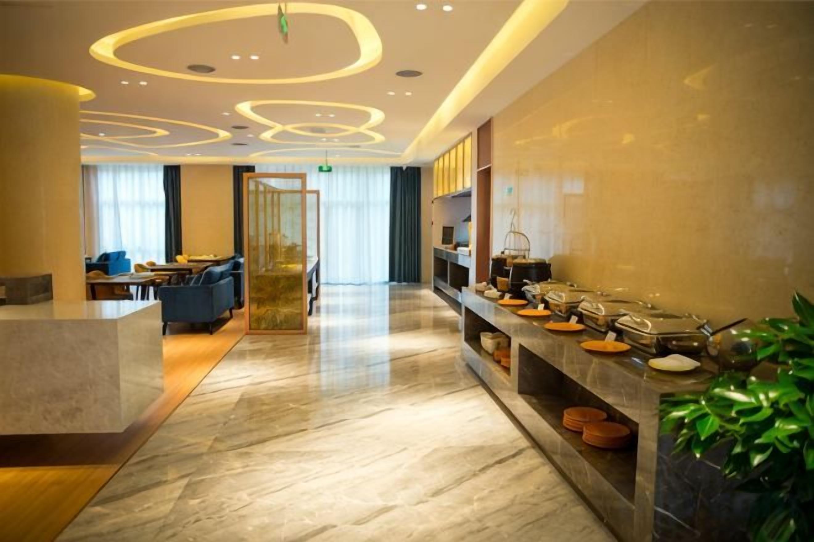 A hotel lobby with a reception desk, seating area, and buffet.
