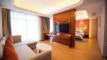 A hotel room with a sofa, a television, a bed, and a small table.