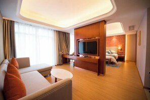 A hotel room with a sofa, a television, a bed, and a small table. - Yuemei Wanxiang Hotel (Zunyi)