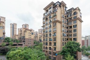 A multi-story residential building with balconies, a courtyard, and surrounding greenery. - Yuemei Wanxiang Hotel (Zunyi)