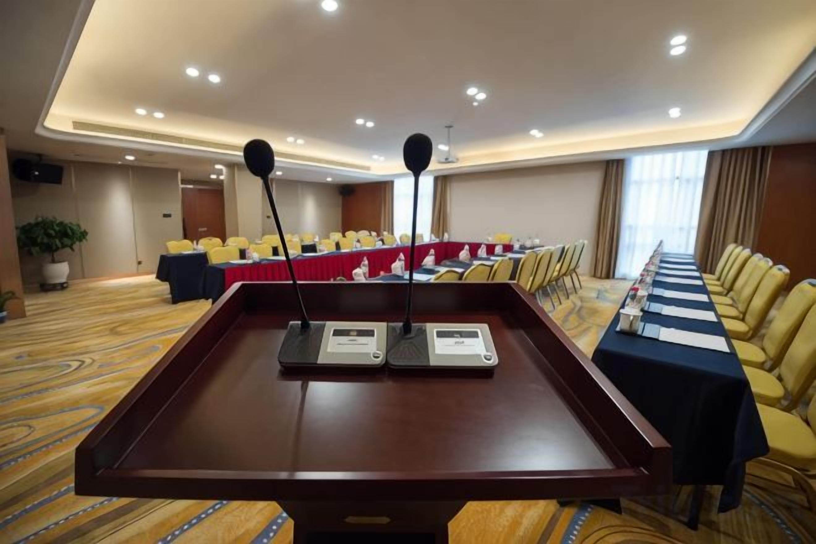 A conference room with a long table, microphones, and yellow chairs.