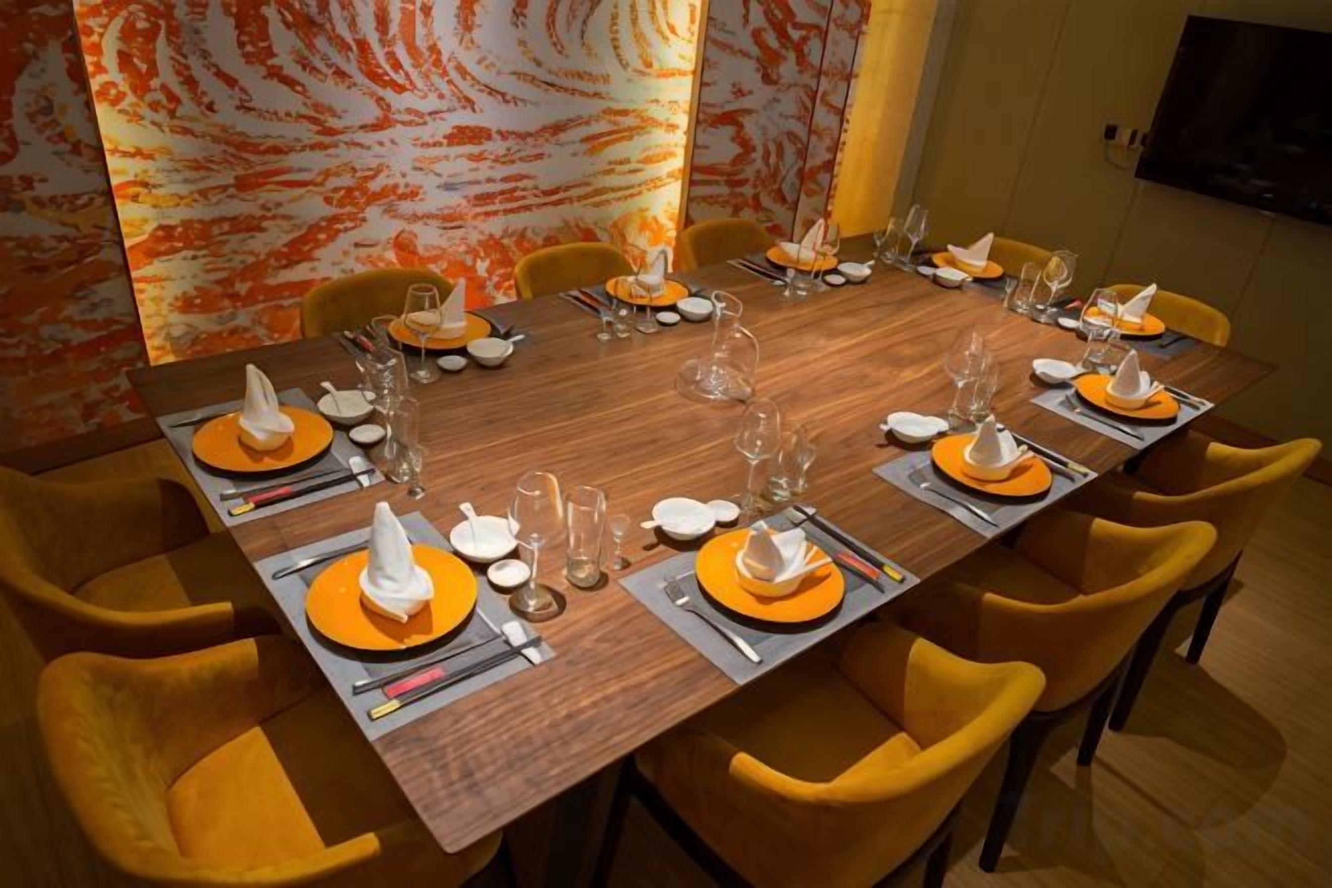 A dining table set for a meal with chairs, plates, cutlery, and glasses.