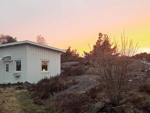 A white building with a window and a door, surrounded by rocks and sparse vegetation. - 4 Person Holiday Home in Kyrkesund (Kyrkesund)