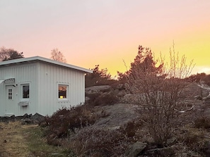 A white building with a small window, surrounded by rocky terrain and sparse vegetation. - 4 Person Holiday Home in Kyrkesund (Kyrkesund)