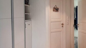 A white wardrobe with a hanging rack, a white door with a 'WC' sign, and a wooden floor. - 9 Person Holiday Home in Lyngdal (Lyngdal)