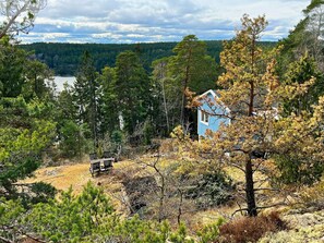 A cabin surrounded by dense forest with a lake in the background. - 5 Person Holiday Home in Tyreso (Tyreso)