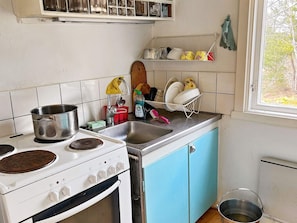 Een keuken met een kookplaat, oven, spoelbak en afwassysteem.