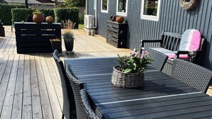 Una terraza con mesa y sillas, una parrilla y plantas en macetas.