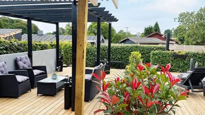 Un patio al aire libre con pérgola, asientos y plantas en macetas.