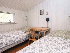 A room with two beds, a wooden table, a lamp, and a window with a view. - 4 Star Holiday Home in Ulfborg (Ulfborg)