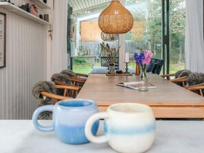 A dining area with a wooden table, chairs, and a hanging light fixture. - 4 Star Holiday Home in Ulfborg (Ulfborg)