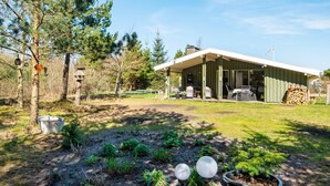 A modern house with a covered porch, a garden with various plants, and a stack of firewood. - 4 Star Holiday Home in Ulfborg (Ulfborg)