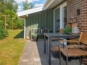 An outdoor patio with a table and chairs, a wooden bench, and a potted plant.