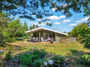 A house with a covered patio, outdoor seating, and a garden. - 4 Star Holiday Home in Ulfborg (Ulfborg)