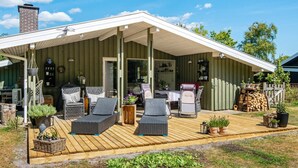 A covered outdoor seating area with wicker furniture and potted plants. - 4 Star Holiday Home in Ulfborg (Ulfborg)