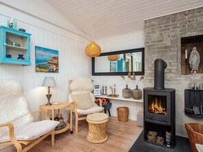 A cozy living room with a fireplace, wooden furniture, and a painting on the wall. - 4 Star Holiday Home in Ulfborg (Ulfborg)