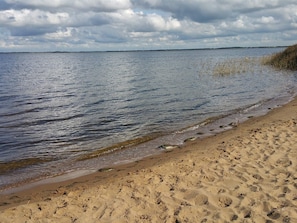 Une plage à l’eau claire, avec un rivage sablonneux et un ciel nuageux.