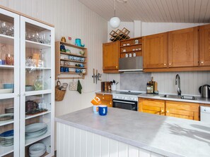 A kitchen with wooden cabinets, a countertop, and various kitchen utensils.