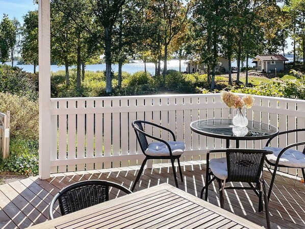 A deck with a table and chairs, overlooking a body of water and trees.