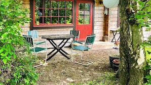 A wooden cabin with a red door, a table, and four chairs in front. - 6 Person Holiday Home in Blentarp (Blentarp)