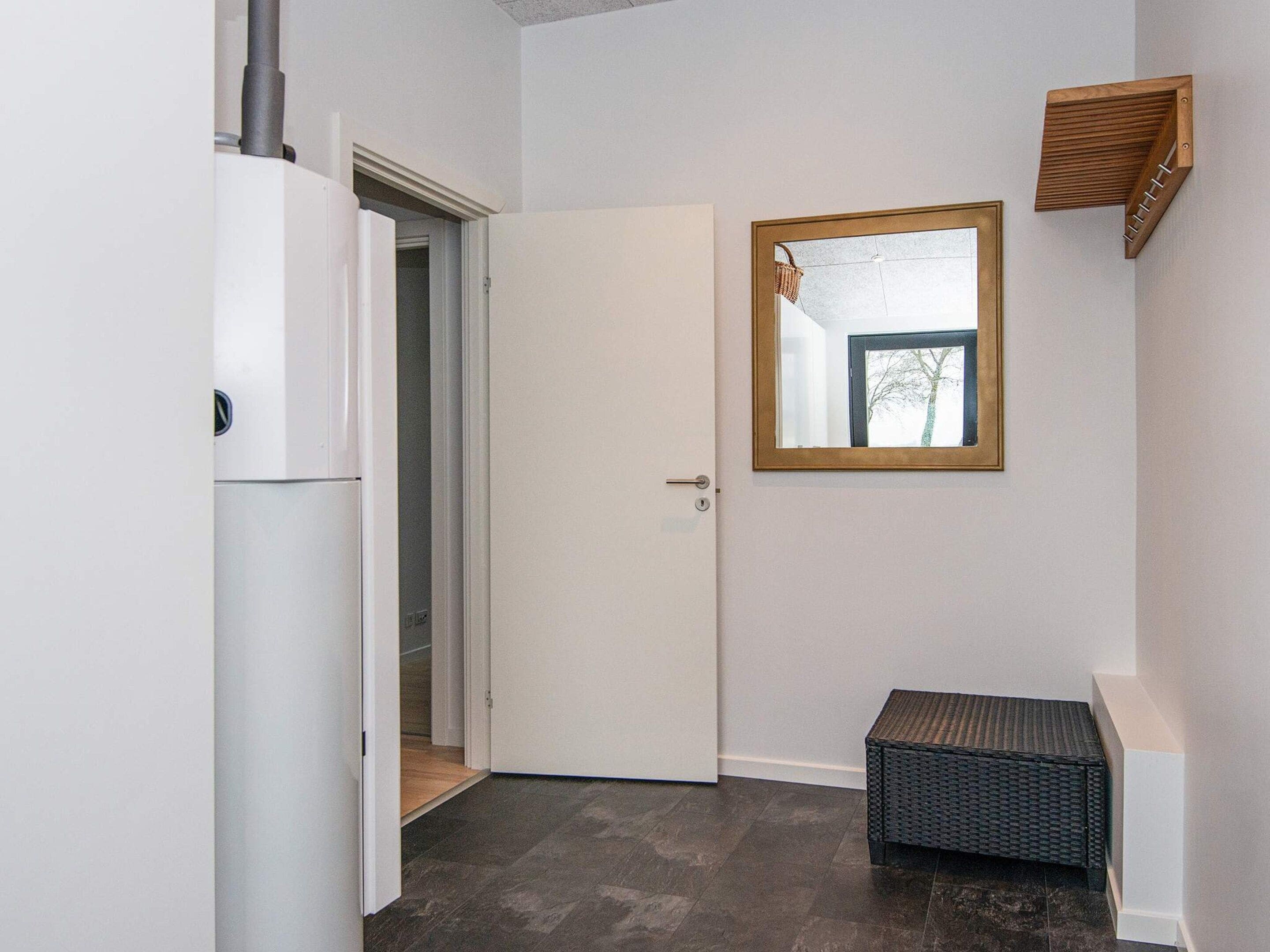 A hallway with a white door, a small bench, and a mirror on the wall.