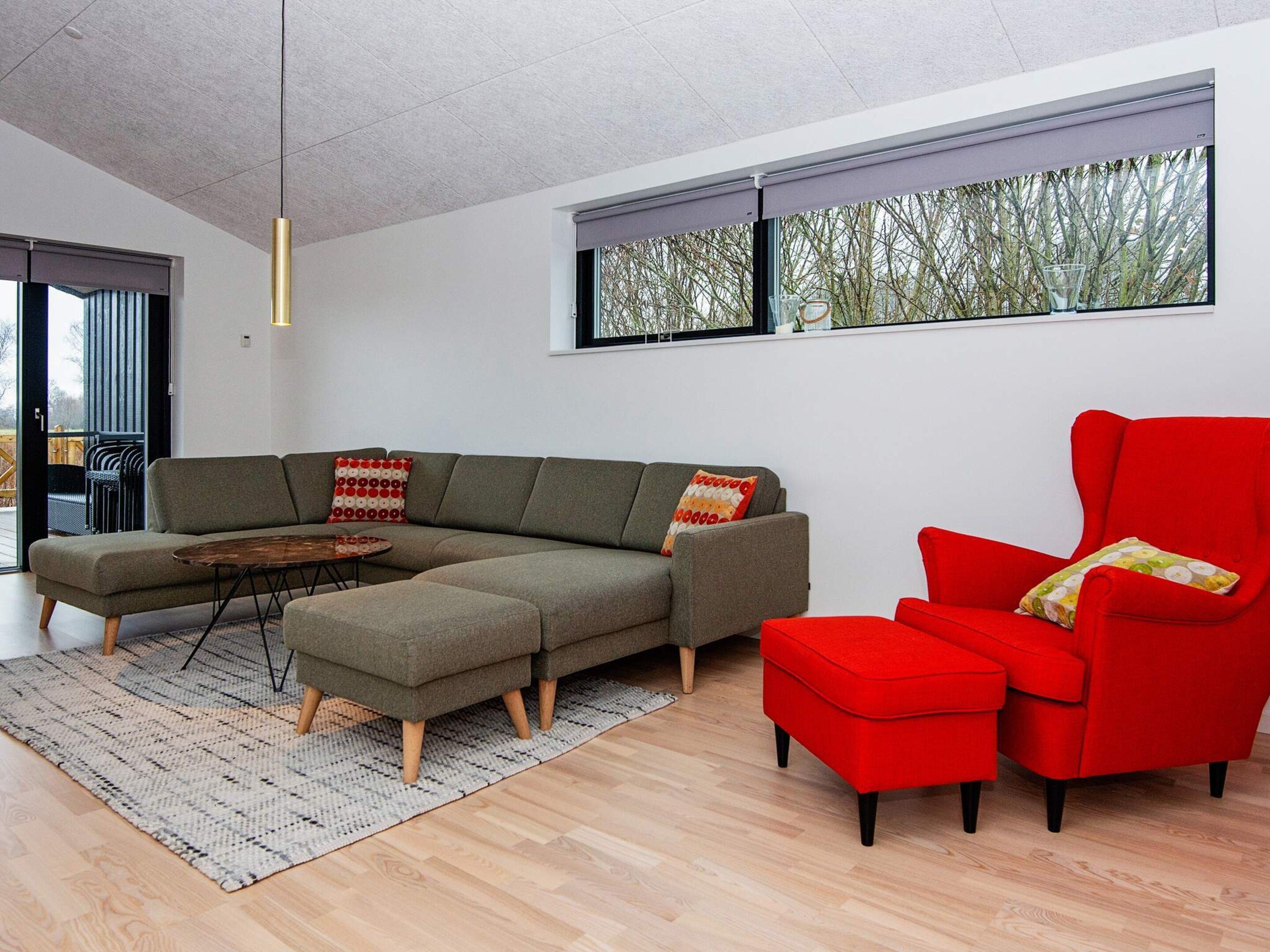 A modern living room with a sectional sofa, a red armchair, and a small round table.