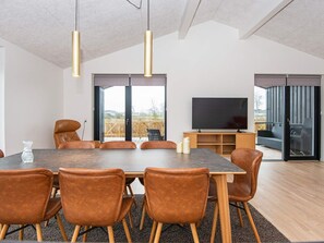 A modern dining area with a large table, leather chairs, pendant lights, and a television. - 8 Person Holiday Home in Aabenraa (Aabenraa)