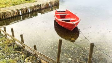 A red boat tied to a wooden dock extending into calm water.