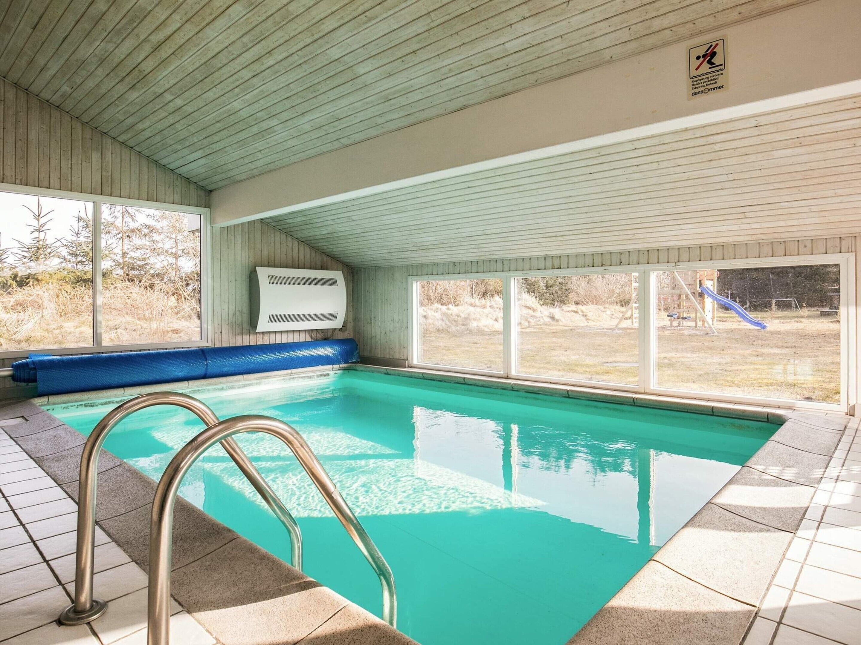 Ein Hallenbad mit klarem, blauem Wasser, einer blauen Matte und einer Metallleiter.