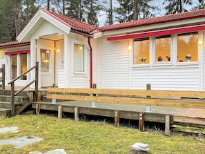 Un bâtiment blanc avec un toit rouge, des marches en bois et une terrasse en bois.