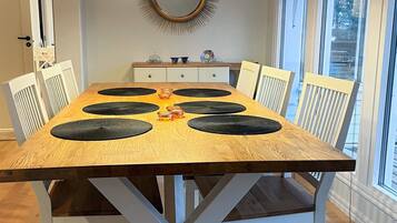 Una mesa de comedor con manteles individuales negros, sillas blancas y lámparas colgantes.