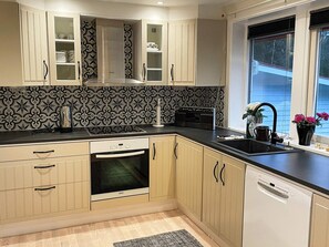 A modern kitchen with a built-in oven, a dishwasher, and a window with a view. - 4 Star Holiday Home in Prassebo (Prässebo)