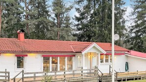 Un bâtiment d’un seul étage, avec un toit recouvert de tuiles rouges, un porche abrité et un espace extérieur clôturé.