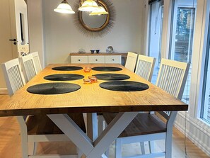 Une table à manger avec des sets de table noirs, des chaises blanches et un miroir décoratif au-dessus.