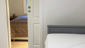 Un dormitorio con una cama, una puerta que da a otra habitación y una ventana con cortinas.