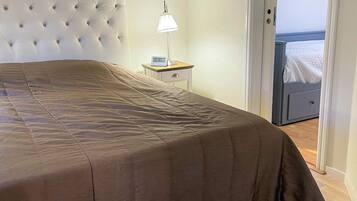 A bedroom with a tufted headboard, a bedside table with a lamp, and a bed with a brown bedspread.