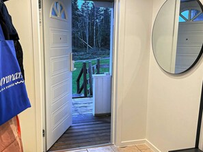 A hallway leading to a deck with a view of trees, a wooden staircase, and a door with a handle. - 4 Star Holiday Home in Prassebo (Prässebo)
