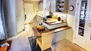 A compact kitchen with white cabinets, a wooden dining table, wicker chairs, and a small countertop. - 4 Star Holiday Home in Maloy (Kinn)